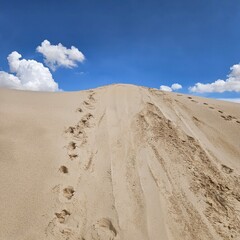 Sandy dune with footprints against a cloudy sky at Monahans Sandhills State Park, Texas