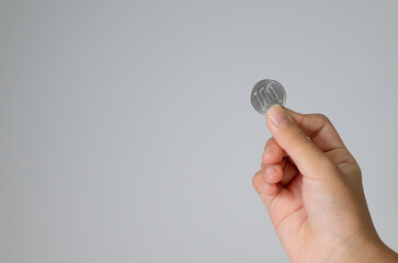Hand holding a 100 yen coin