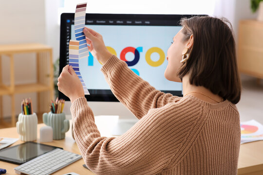 Young female graphic designer working with color samples at table in office - Powered by Adobe