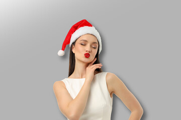 Woman wearing a red Santa hat and white dress poses playfully
