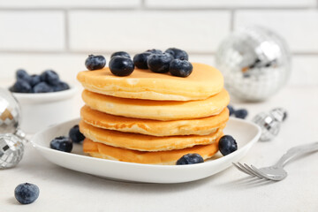 Plate of sweet pancakes with blueberries and Christmas disco balls on white table