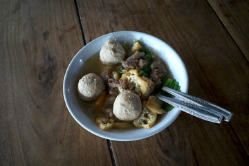 A bowl of meat ball soup, Bakso with fresh vegetables on the old wooden table