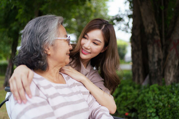 Naklejka premium Asian woman walking with elderly mother in wheelchair in morning.
