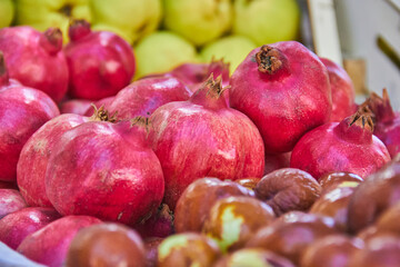 Fresh pomegranates and other fruits displayed at a local Granada market, their vivid red tones contrasting with the surrounding produce. vibrant harvest