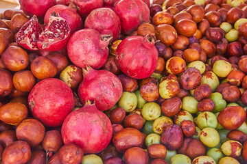 Fresh pomegranates and jujubes displayed together at a market stall in Granada, Spain, creating a vivid mix of red, green, and brown tones. fruits market