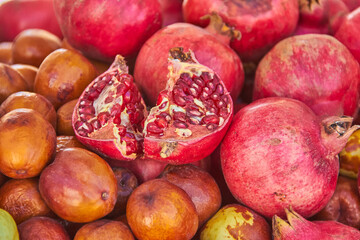 Ripe pomegranates and jujubes displayed together at a market stall in Granada, Spain, highlighting their vivid natural colors and textures. fruits harvest