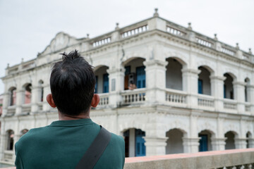 Tourist looking at a Western-style building in Taiwan. Back view, travelling, learning local history. Blur background.