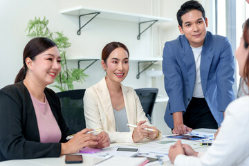 Asian business people collaborating in a modern office meeting room, sharing ideas and analyzing data, showing successful teamwork