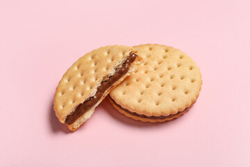Tasty sandwich biscuits with chocolate cream on pink background