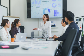 Asian businesswoman discussing performance data with colleagues during a marketing and data...