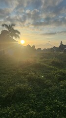 Obraz premium golden sunrise over suburban landscape with mountain silhouettes and grassfields