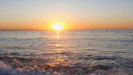 An idyllic view of the ocean during the golden hour. The sunlight spreads across the water, emphasizing the texture of the small waves.