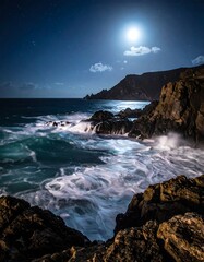 Night shot of waves crashing on rocks under a bright moon and starry sky