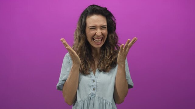 Hispanic woman raises clenched fists and spreads open palms in a vibrant purple studio scene; excitement triumph celebration.