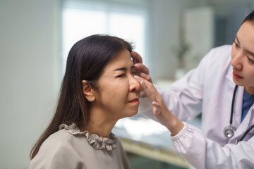 Doctor examining Asian woman's nose, discussing rhinoplasty or cosmetic surgery options during a...