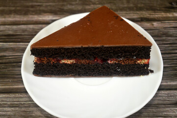 a slice of a chocolate cake, made with chocolate or cocoa and can be flavored with fudge or vanilla cream, a cake with multiple layers with a filling and topped with chocolate ganache