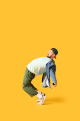 Handsome male hip-hop dancer dancing on yellow background