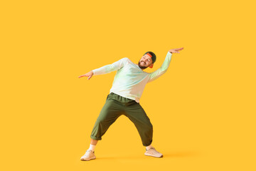 Handsome male hip-hop dancer dancing on yellow background