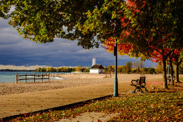 Wooden boardwalk in public park with bench in foreground and iconic leuty lifeguard station in...