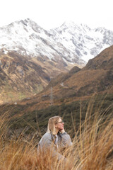 Woman in mountain landscape. A woman sits in tall golden grass in Arthur Pass, New Zealand. 