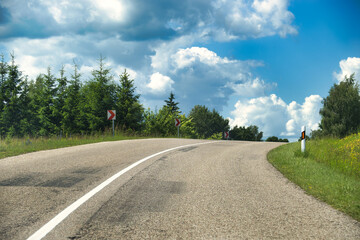 Curving Country Road Winding Through Green Trees Under a Bright Sky On a Sunny Day