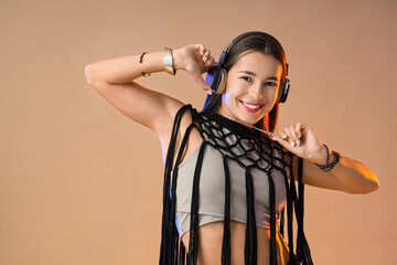 Female hip-hop dancer in headphones on beige background