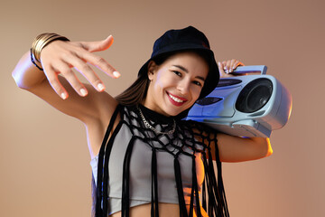 Female hip-hop dancer with boombox on beige background