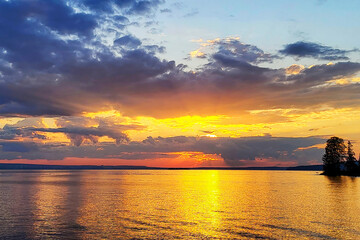 Obraz premium Evening autumn landscape of the sunset over the horizon against the backdrop of the waters of a large lake.