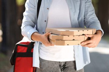 Male courier with food bag and pizza boxes outdoors, closeup
