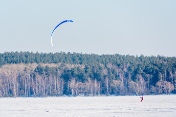 Kite surfer ride on snowboard. Snowkiting in the snow on frozen lake.