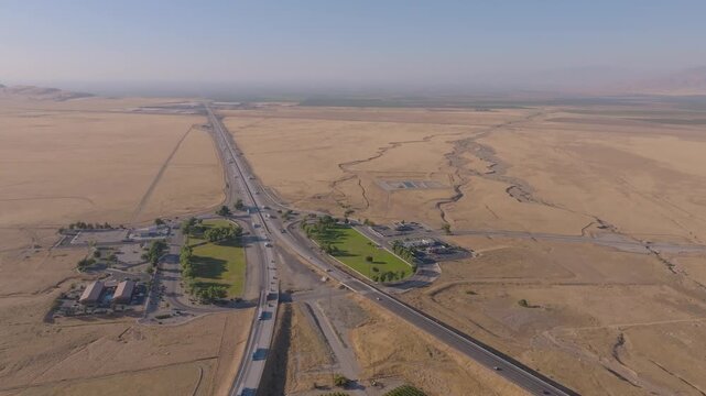 4K aerial shot showing multiple lanes of cars and trucks filling Interstate 5 near Grapevine Road at the north end of Tejon Pass. Highlights the scale and economic importance of California&rsquo;s primary n
