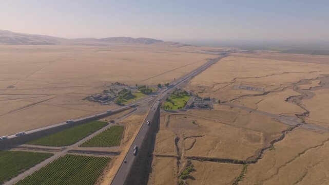 4K aerial shot showing multiple lanes of cars and trucks filling Interstate 5 near Grapevine Road at the north end of Tejon Pass. Highlights the scale and economic importance of California&rsquo;s primary n