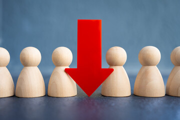 Wooden human figures with a large red down arrow represent job loss, downsizing, unemployment, layoffs, resignation, staff reduction, economic crisis, and workforce impact in business concept. © sommart