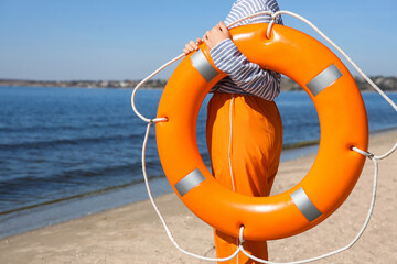 Female sailor with lifebuoy ring on sea beach