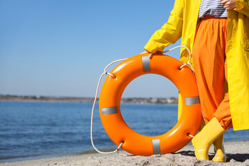 Female sailor with lifebuoy ring on sea beach