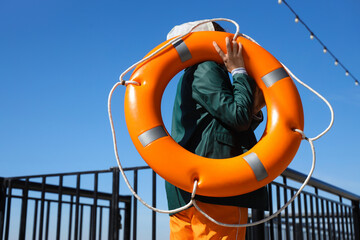 Female sailor with lifebuoy ring on embankment