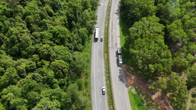 Drone footage of the aerial view of a winding road cutting through lush green forest. Scenic highway number 304 in Thailand links the Bangkok area to Nakhon Ratchasima in the northeastern region
