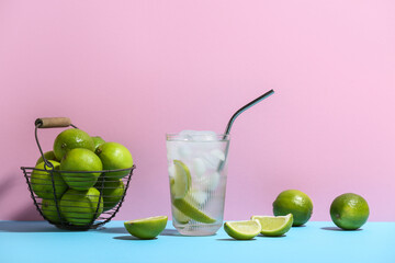 Glass of lime infused water on blue table against pink background