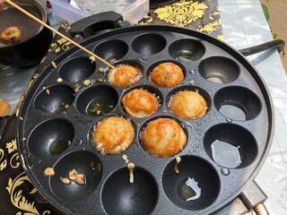 Cooking Takoyaki in a Pan with Skewers
