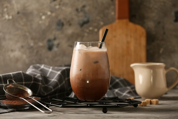 Glass of cold cocoa drink and cubes of sugar on grey background