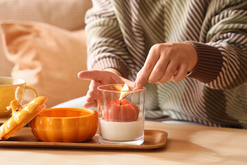 Young woman lighting up candles on table in living room, closeup