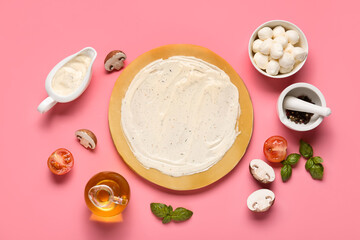 Pizza dough with tasty sauce and ingredients on pink background