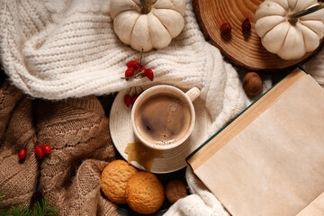 Composition with mug of tasty coffee, notebook and pumpkins on sweaters as background