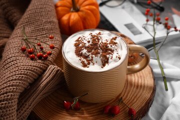 Composition with mug of tasty coffee and sweater on white fabric as background, closeup