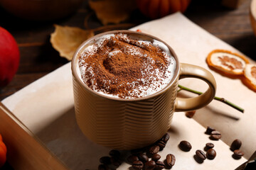 Mug of tasty coffee, notebook and beans on wooden table, closeup