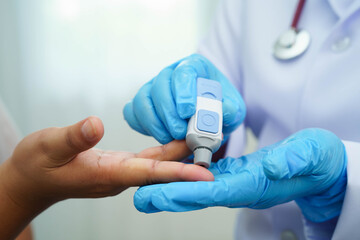 Asian woman self testing to check blood sugar level diabetes by digital lancet on finger at home. © Pakawadee