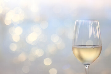 a glass of white wine, a background under the summer sun, a bokeh and sun glare, a blurred abstract background