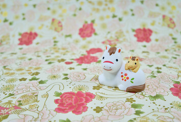 可愛い馬の置物と和柄の背景の年賀状素材