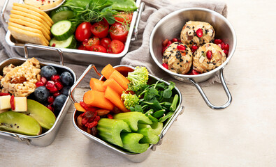 Boxes containing fresh fruits, vegetables, sandwiches, and nuts.