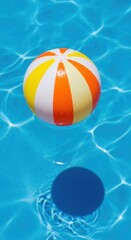Bright beach ball floating in clear blue water on a sunny day near a relaxing poolside